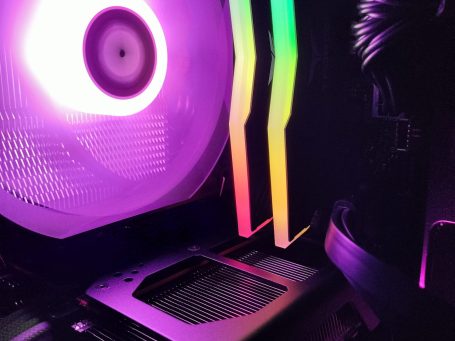 Close-up of a glowing computer case fan with colorful RGB lighting.