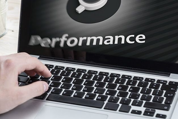 Hand typing on a laptop keyboard, with the word "Performance" displayed on the screen.