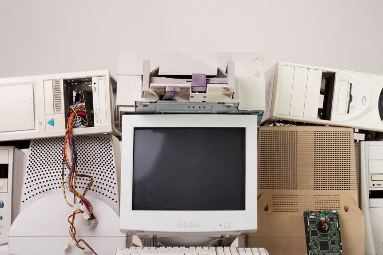 Old computer parts stacked together, including a monitor, floppy drives, and circuit boards.