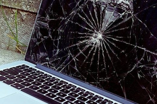 Close-up of a laptop screen with a cracked and shattered surface.